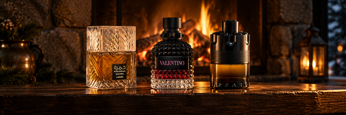 Lattafa Khamrah Qahwa, Valentino Born in Roma and Azzaro The Most Wanted fragrance bottles on a dark wood mantel beside a burning log fire